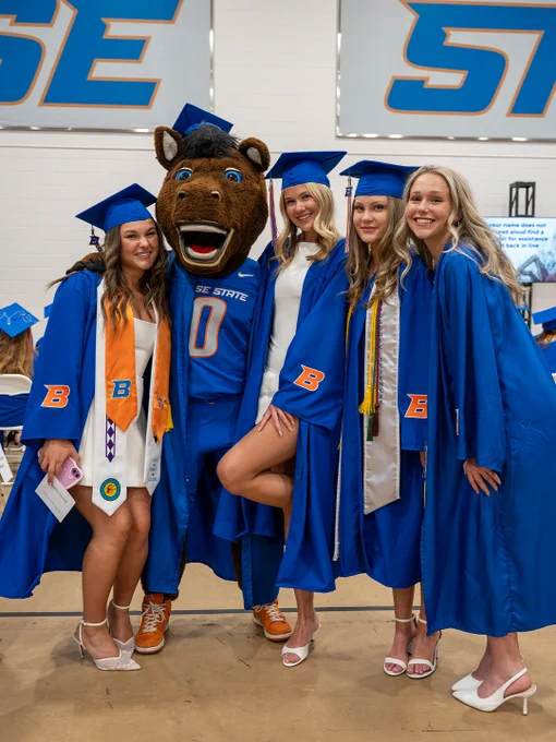 Group of Boise State graduates posing with Buster Bronco mascot before commencement.
