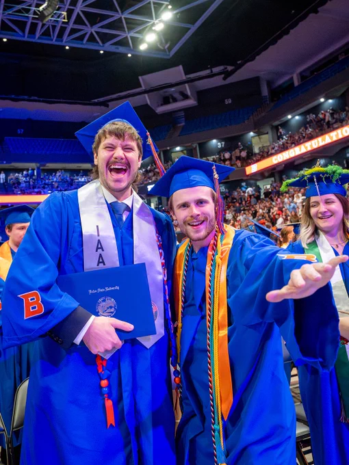Two Boise State graduates celebrating after their commencement ceremony in Extra Mile Arena. 