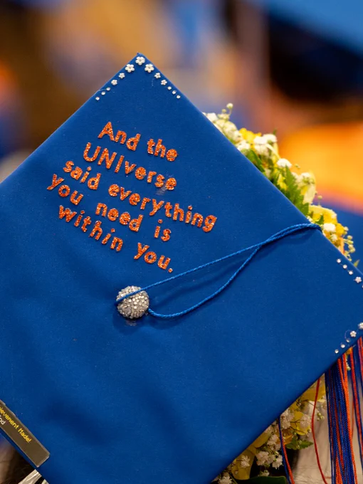 Boise State blue graduate mortar board cap decorated with the quote “And the UNIverse said everything you need is within you.” 
