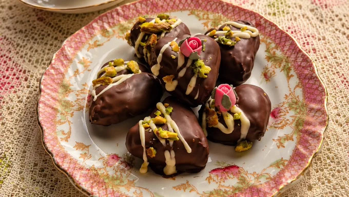 Chocolate date hearts with pistachios and white chocolate on a floral vintage plate.