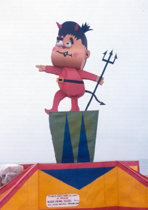 
Dimoni de 1976, amb el cartell del premi del Primer Concurso Infantil de Dibujos del Dimoni, que va guanyar Roser Coronel, alumna del Colegio Nacional Cardenal Gomà, avui l'Escola Feliu i Vergés. (Fotografia de: festesdemaig.cat)