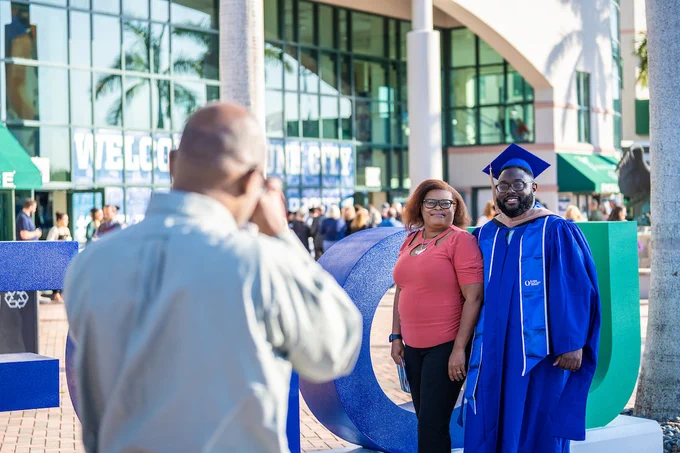 a photo of a dad taking a picture of a mom and son at graduation