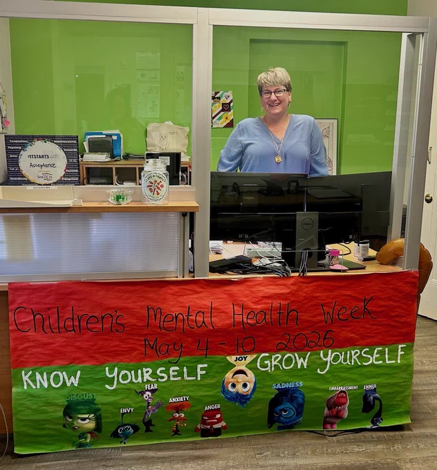 Reception desk decorated with a colorful banner for Children's Mental Health Week 2026 featuring characters representing emotions like joy, fear, and sadness.