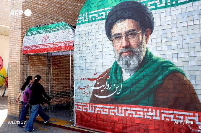 Women walk past a banner depicting Iran's supreme leader Ayatollah Mojtaba Khamenei along a street Tehran, on May 6, 2026.