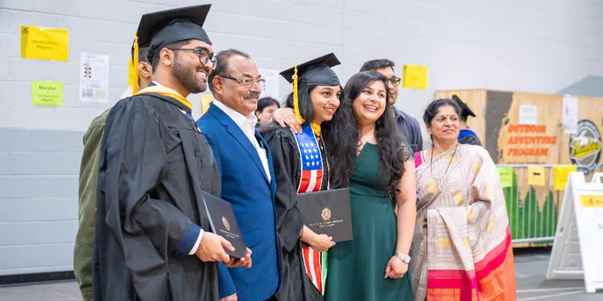 Two Michigan Tech graduates pose with their family members after a commencement ceremony. 