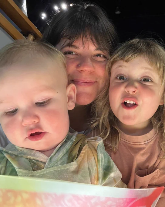A candid close-up of a mother and two young children sharing a moment of discovery while looking at an exhibit together.