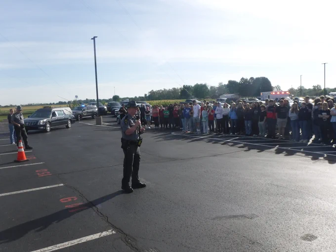 A trooper is standing in front of students outside at Eastern Brown High School. The trooper is giving a Drive to Live presentation. 