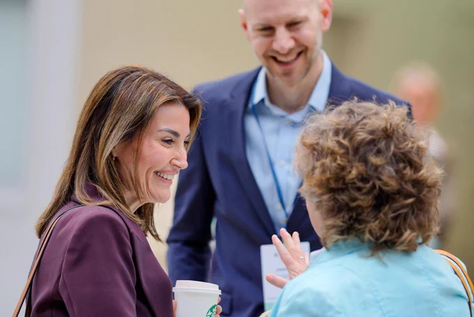 3 attendees having a conversation and smiling