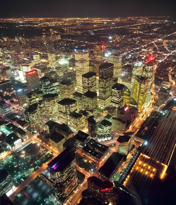 Aerial night view of a bustling city skyline with illuminated skyscrapers and streets stretching into the distance.