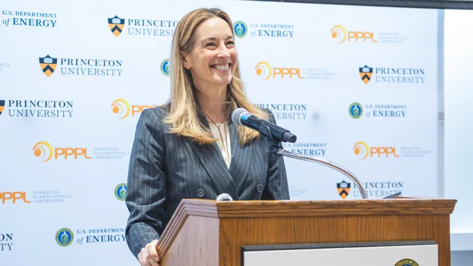 NJ Governor Mikie Sherrill smiling at a podium with multiple logos in the background, including Princeton University, U.S. Department of Energy, and PPPL (Princeton Plasma Physics Laboratory).