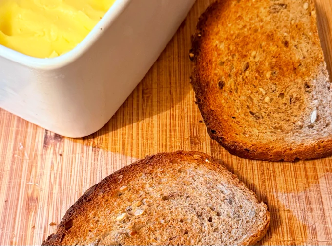 Homemade bread toasted next to a ceramic butter dish