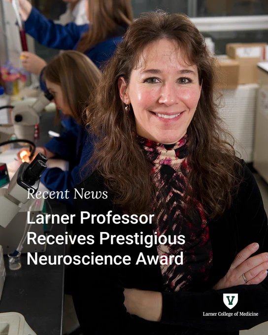 A person standing in a lab, smiling at the camera. 