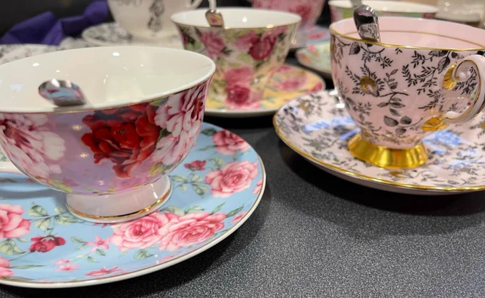 A close-up of several ornately decorated teacups and saucers on a table. 