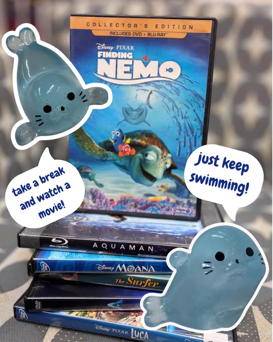 A stack of DVDs. Stickers of resin seals are layered on top with speech bubbles that say “take a break and watch a movie” and “just keep swimming!”