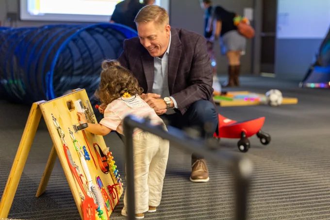 Dr. Brad Schnautz interacts with a toddler using a sensory board during Babies Day Out.