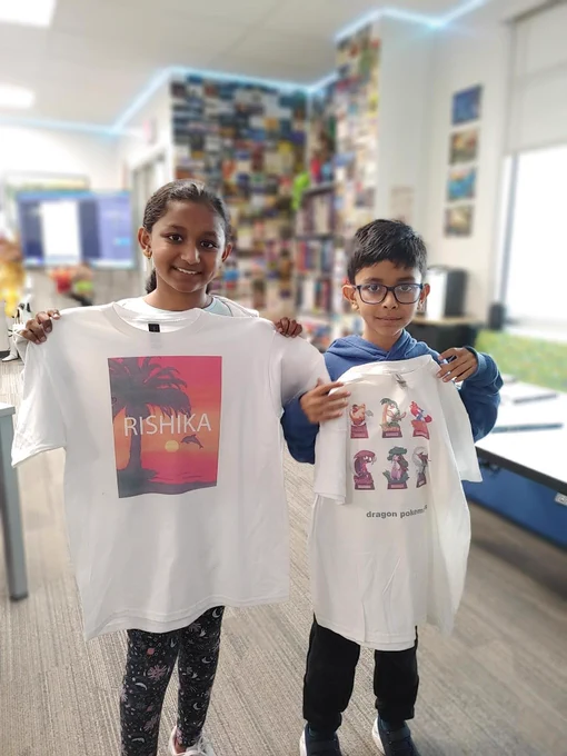 Two children wearing custom-made t-shirts, one with a graphic design and the other with various cartoon characters, standing in a room filled with art and photographs.