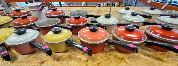 Various colorful pots and cookware on a table at Surplus.