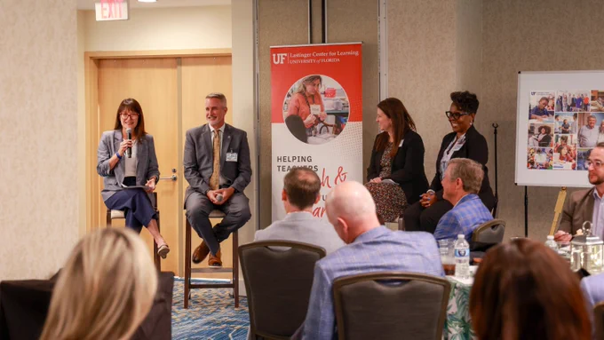 Four people seated in front of a room for a panel.