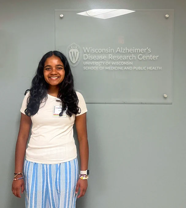 Summer internship student standing in front of a sign for the Wisconsin Alzheimer's Disease Research Center in Madison, Wisconsin.