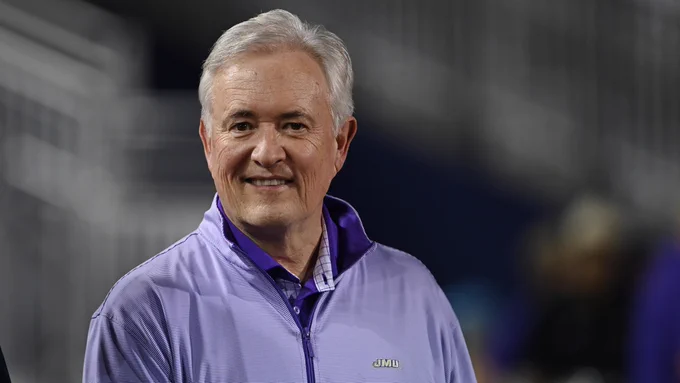 Former Director of Athletics, Jeff Bourne smiles at camera on the sidelines of a JMU Football game. 