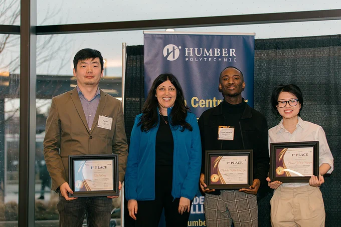 A group of people stand together. Some are holding up certificates.
