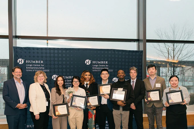 A group of people stand together. Some are holding up certificates.
