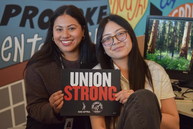 Sun-Times Guild members and audience engagement specialists Vanessa Lopez and Phyllis Cha hold a sign that says “UNION STRONG” with both the SAG-AFTRA and the Sun-Times Guild logos on it.