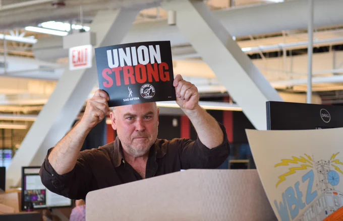 Sun-Times Guild member and environmental reporter Brett Chase holds a sign that says “UNION STRONG” with both the SAG-AFTRA and the Sun-Times Guild logos on it.