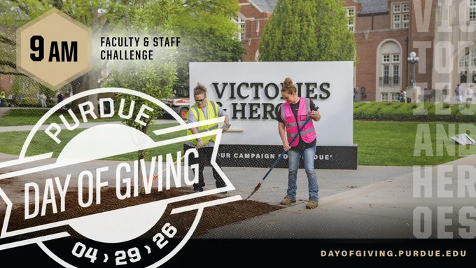 Two Purdue staff members from Administrative Operations in safety vests spreading mulch in the  Purdue Memorial Union front lawn landscaping.
