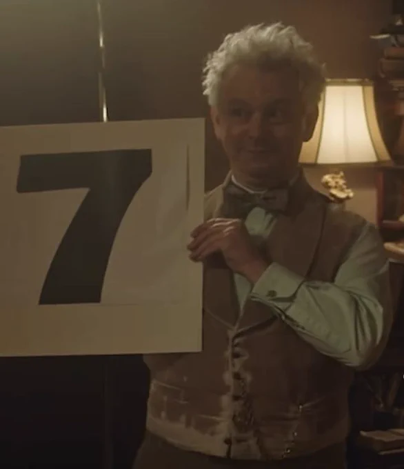 Aziraphale holding out a sign with the number 7