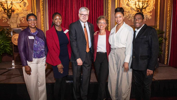 A man in a suit poses for a photo with a group of five people