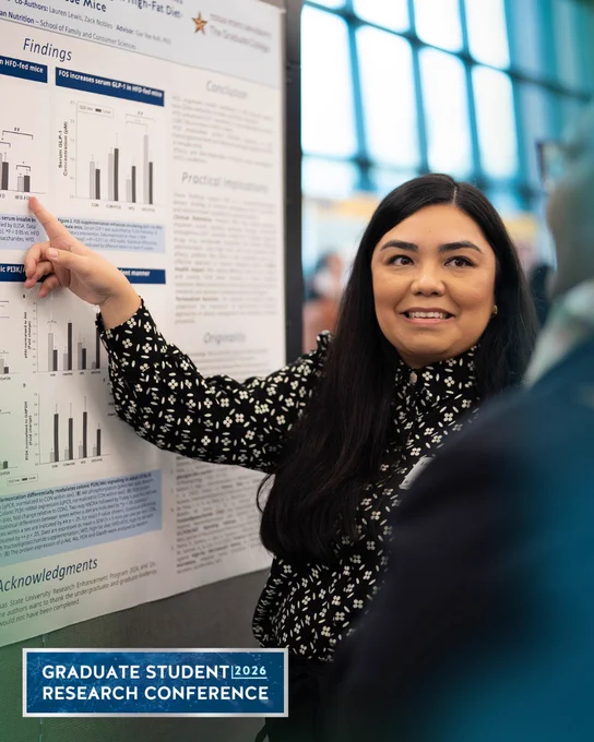 Graduate student presenting detailed research findings on a scientific poster at a conference.