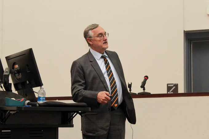 Gabor Tigyi leaning on a podium while presenting to a crowd.