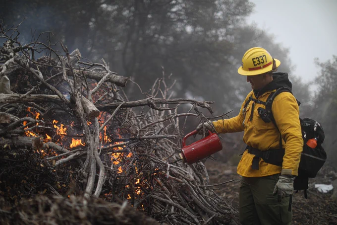 Firefighter igniting a pile of debris for a controlled burn on the Cleveland National Forest. 