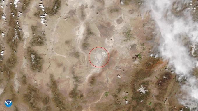 Satellite image of a lake (within a red circle) in a desert with the NOAA logo in the bottom left-hand corner.