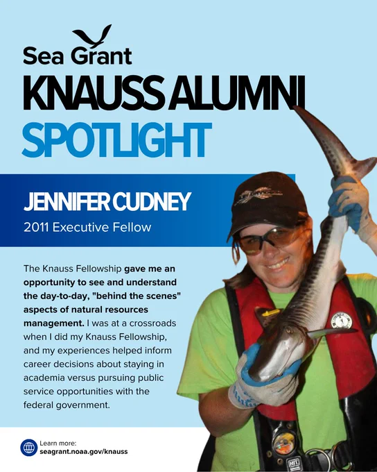 A Sea Grant "Knauss Alumni Spotlight" card for Jennifer Cudney, a 2011 Executive Fellow. The card features a photo of Jennifer smiling while wearing a green shirt, a red life vest, a baseball cap, and safety glasses as she holds a large sturgeon.

The text reads: "The Knauss Fellowship gave me an opportunity to see and understand the day-to-day, 'behind the scenes' aspects of natural resources management. I was at a crossroads when I did my Knauss Fellowship, and my experiences helped inform career decisions about staying in academia versus pursuing public service opportunities with the federal government."

Link at bottom: seagrant.noaa.gov/knauss