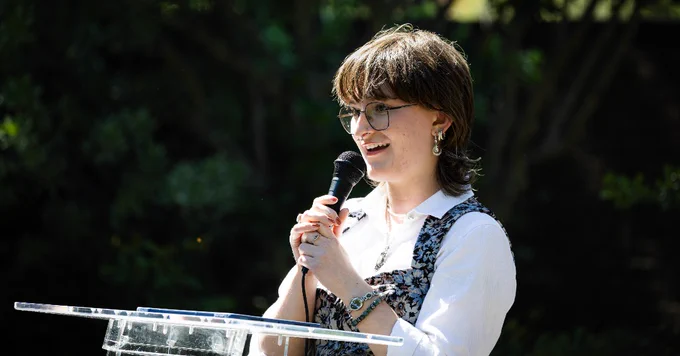 Student speaker holding microphone at a podium during the National Fellowships Celebration.