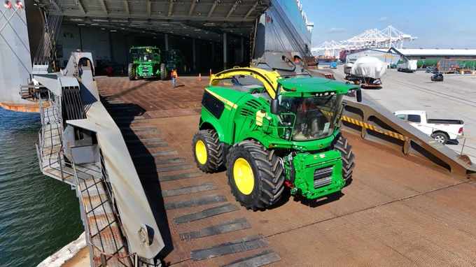 Farm and construction machinery is driven down a vessel’s ramp at the Port of Baltimore, demonstrating roll-on/roll-off cargo operations.