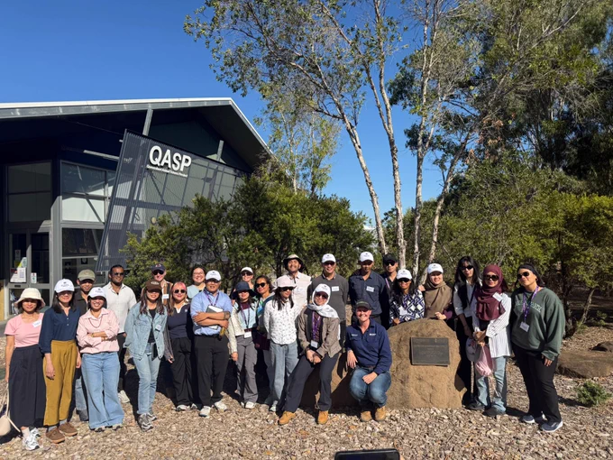 Group smiling in front of the Queensland Animal Science Precinct (QASP) building.
