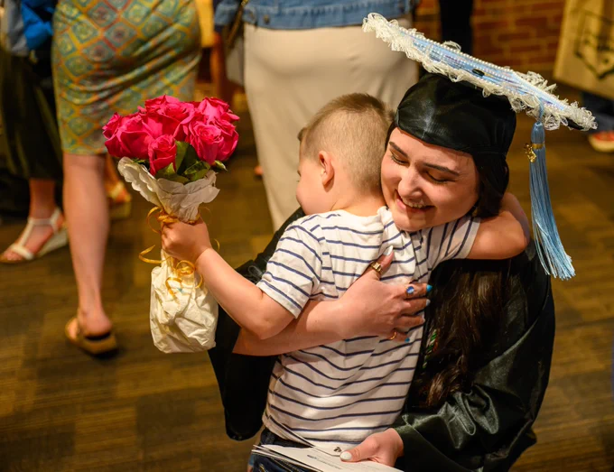 Ohiu University graduate embraces a family member in a hug.