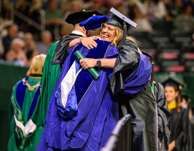 Ohiu University graduate embraces a friend in a hug.
