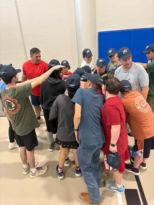 Many people gathered close together with their hands in for a team huddle.
