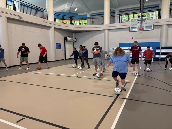 A photo of many people playing futsal in a gymnasium.