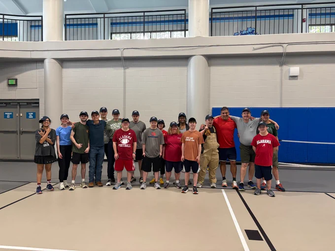 Many people gathered for a group photo in a gymnasium. 