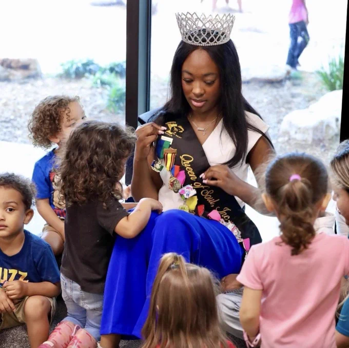 2026 San Antonio Queen of Soul, Kamarie Crawford, showing her Fiesta medals to children.
