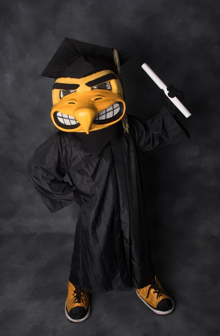 Herky wearing graduation cap and gown.