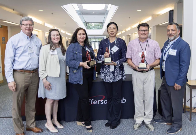 A group of people, several of which are holding glass trophies. 