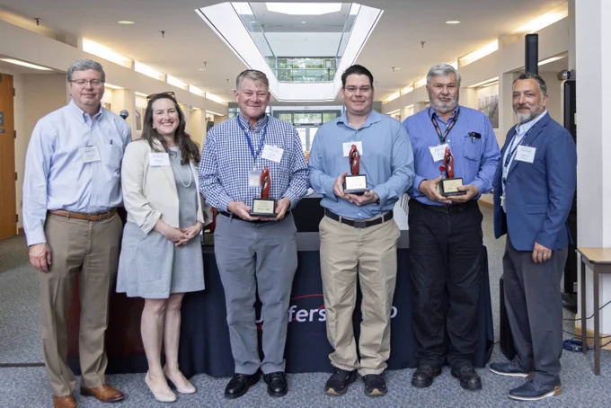 A group of people, several of which are holding glass trophies. 