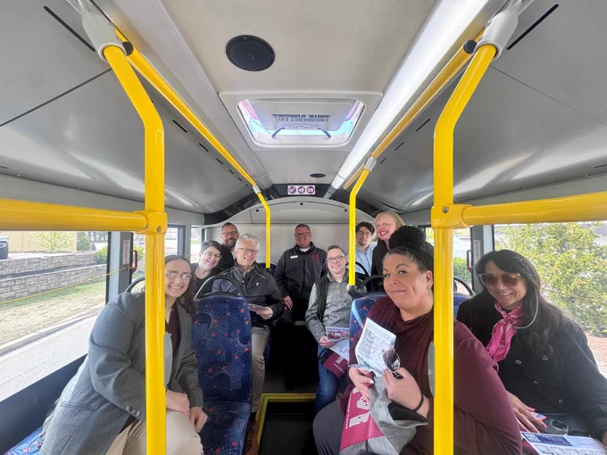 People smiling at the camera while seated in the back of a Manchester Transit Authority bus.