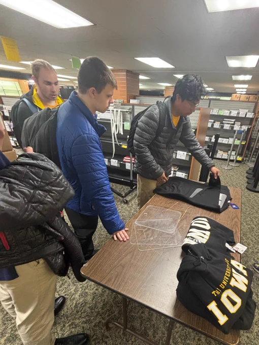 UI REACH students practice folding shirts at Iowa Book.